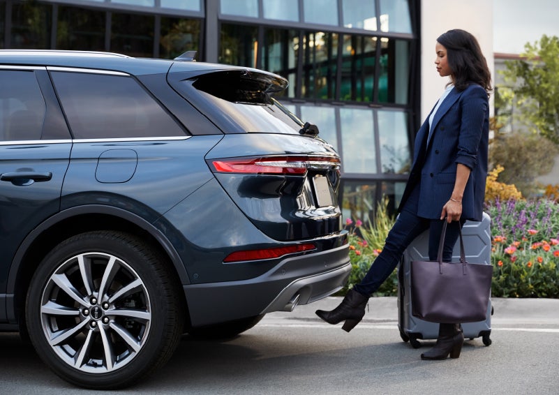 A woman with luggage and a bag opens the available hands-free liftgate by kicking her foot under the bumper | Performance Lincoln Bountiful in Bountiful UT