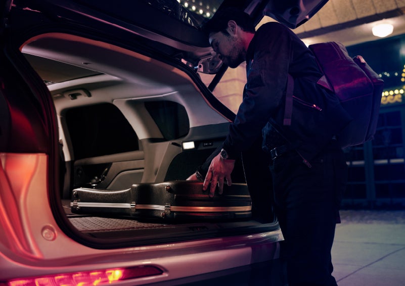 A musician slides his guitar case into the cargo space of a 2022 Lincoln Corsair with the rear seats folded flat to provide ample cargo space | Performance Lincoln Bountiful in Bountiful UT